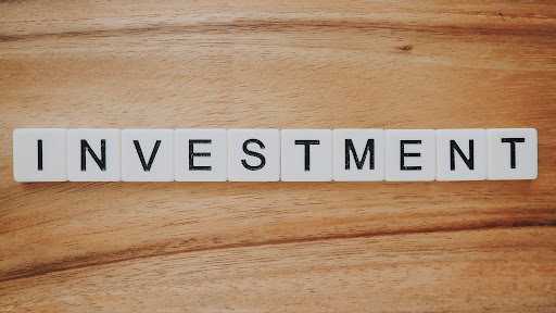 White letter tiles on a wooden surface spell the word “INVESTMENT” in uppercase black letters, highlighting strategies that can help you reduce your RMDs for more efficient retirement planning.